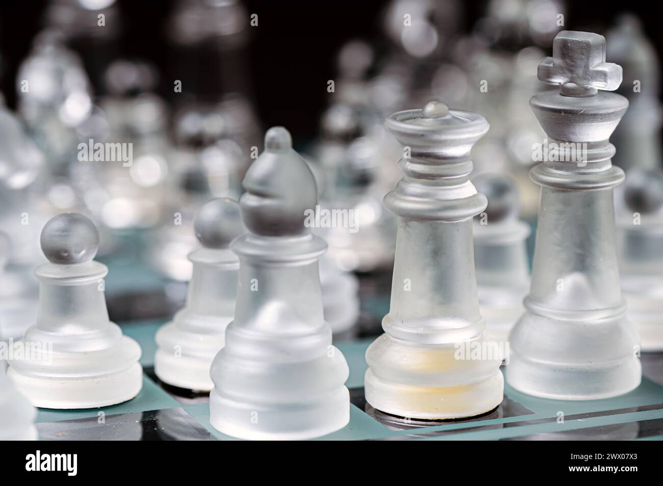 verre transparent, pièces d'échecs transparentes sur un damier, mise au point sélective, gros plan, isolé sur le noir Banque D'Images