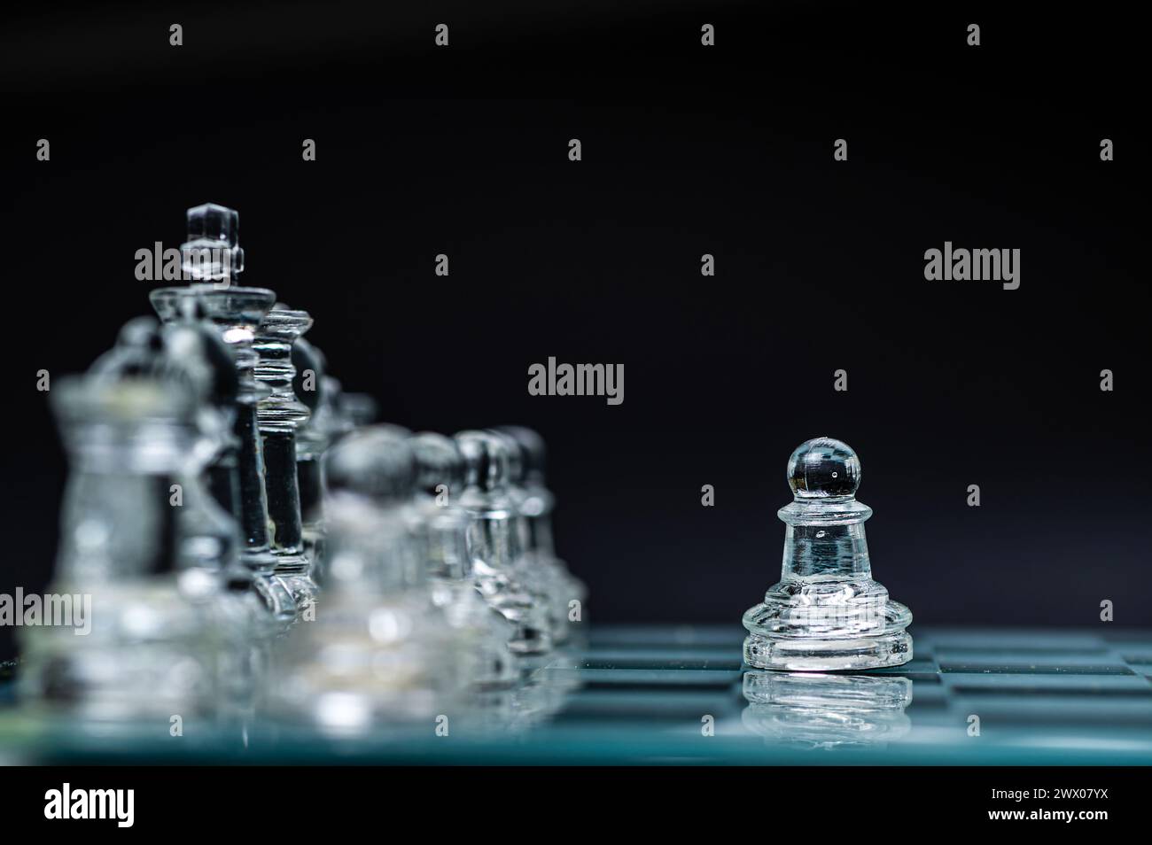 échecs en verre transparent sur fond sombre, mise au point sélective sur la pièce de pion, gros plan Banque D'Images