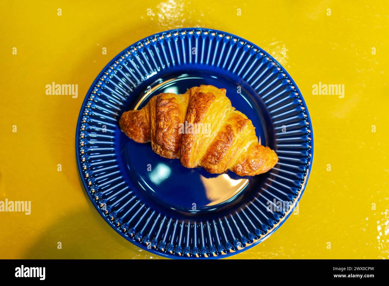 croissant coloré bleu jaune plat couché dans une boulangerie sur une assiette . Banque D'Images