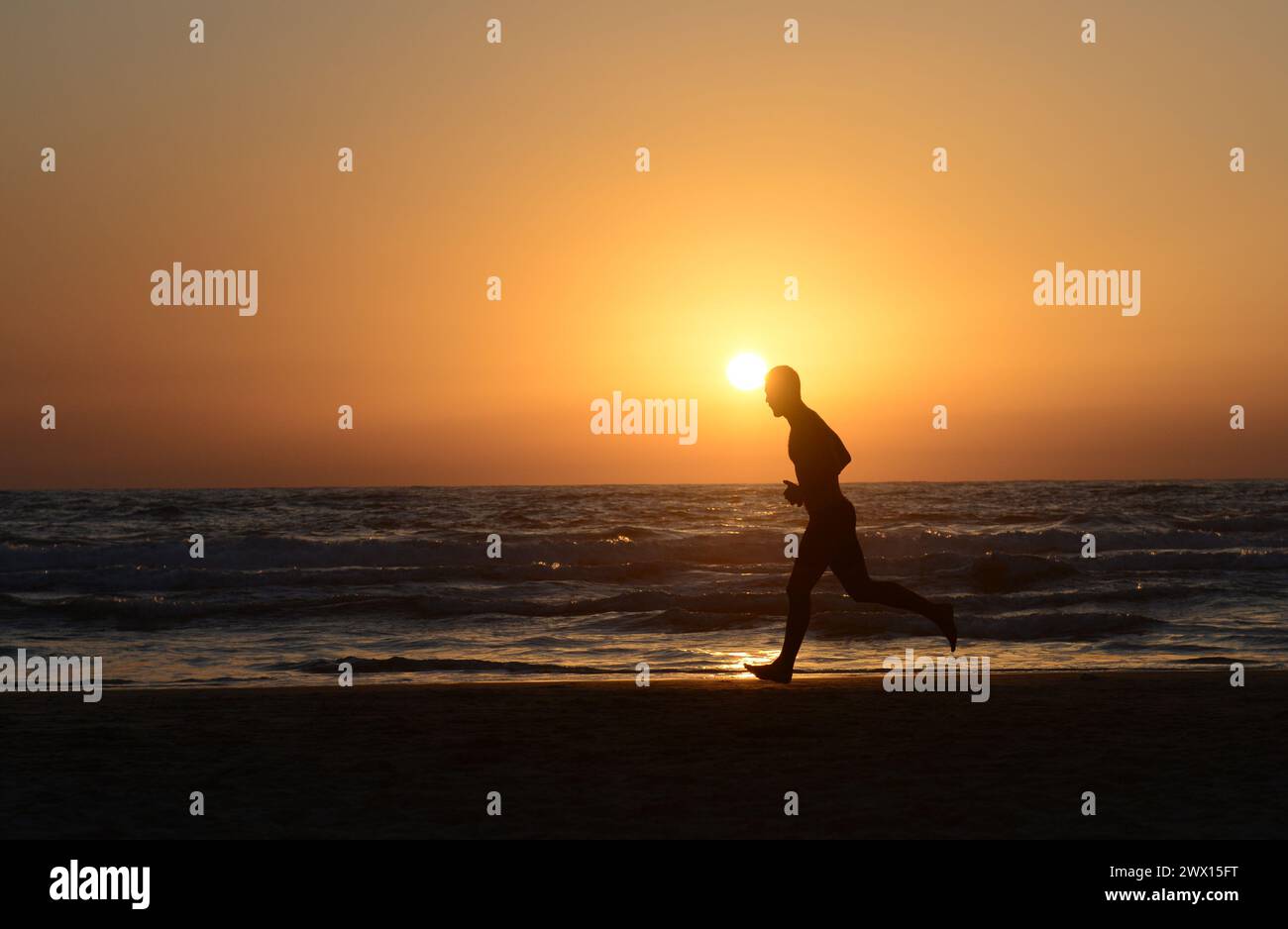 Jogging sur la plage pendant le coucher du soleil à tel-Aviv, Israël. Banque D'Images