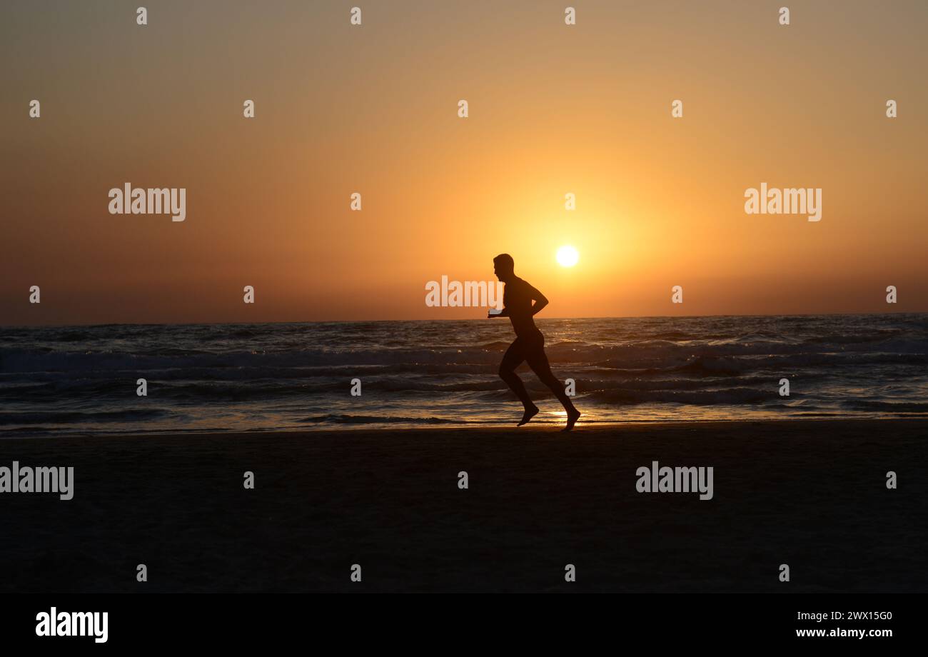 Jogging sur la plage pendant le coucher du soleil à tel-Aviv, Israël. Banque D'Images