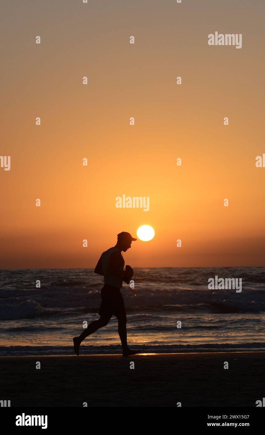 Jogging sur la plage pendant le coucher du soleil à tel-Aviv, Israël. Banque D'Images