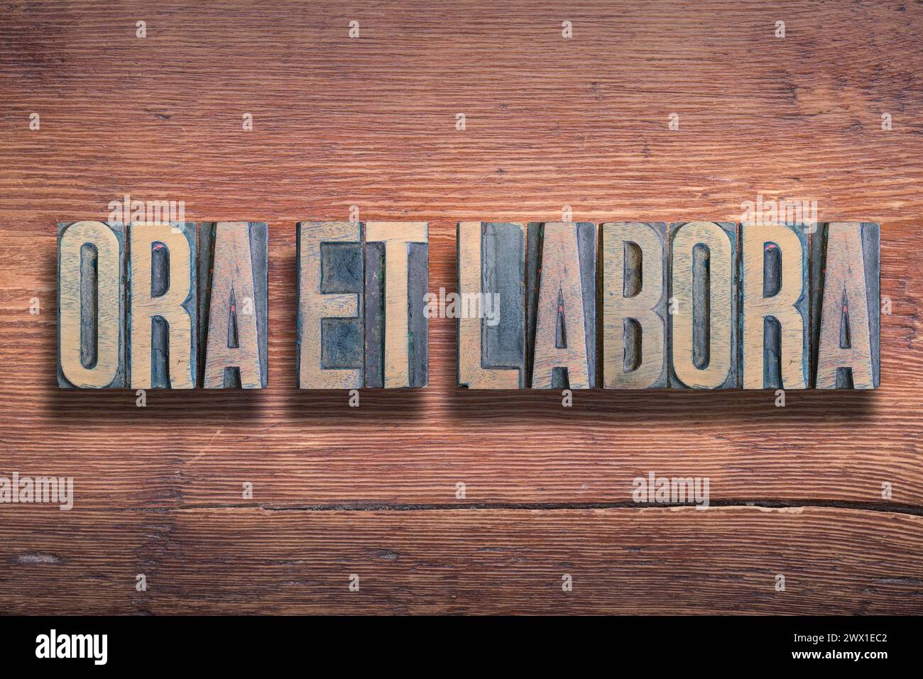 Ora et labora ancienne phrase latine signifiant prier et travailler, combinée sur une surface en bois verni vintage Banque D'Images