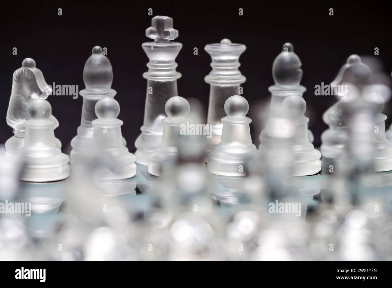 verre transparent, pièces d'échecs transparentes sur un damier, mise au point sélective, gros plan, isolé sur le noir Banque D'Images