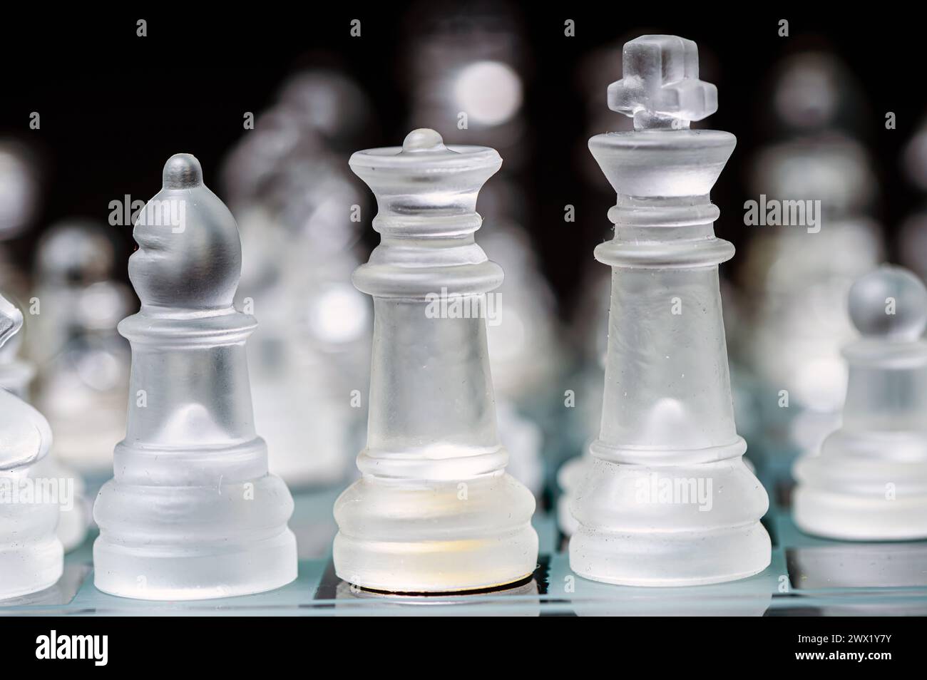 verre transparent, pièces d'échecs transparentes sur un damier, mise au point sélective, gros plan, isolé sur le noir Banque D'Images