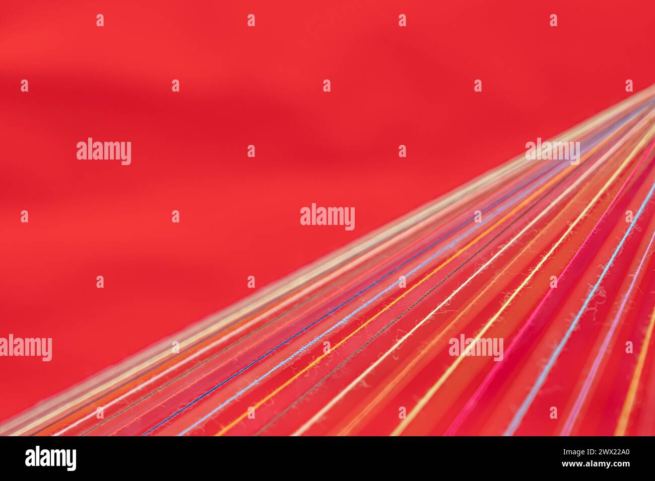 Convergent fil à coudre multicolore sur un fond rouge Banque D'Images
