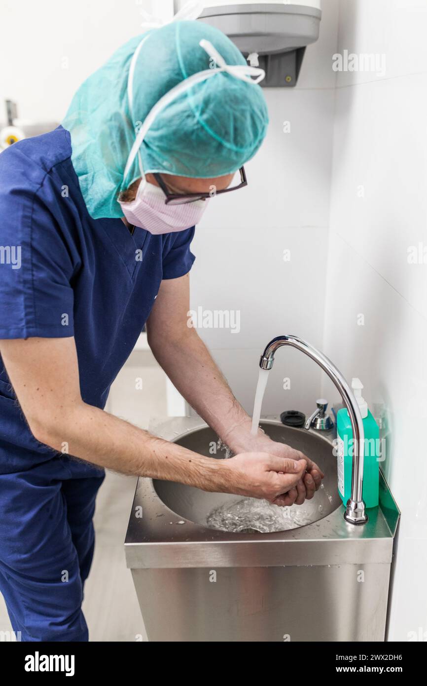 vétérinaire homme chirurgien dans les vêtements épi se préparant à opérer le lavage des mains dans l'évier de la clinique Banque D'Images