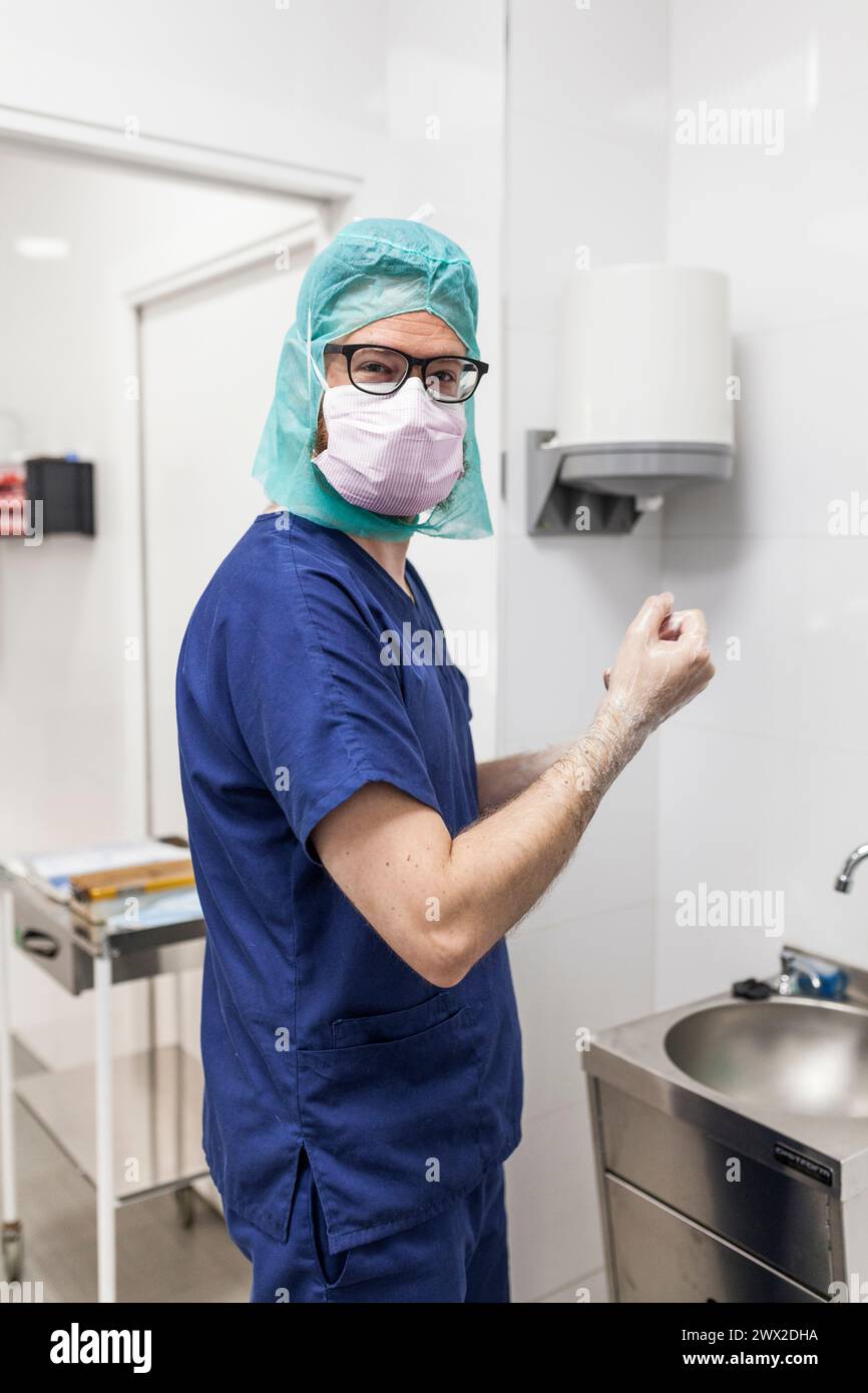 vétérinaire homme chirurgien dans les vêtements épi se préparant à opérer le lavage des mains dans l'évier de la clinique Banque D'Images