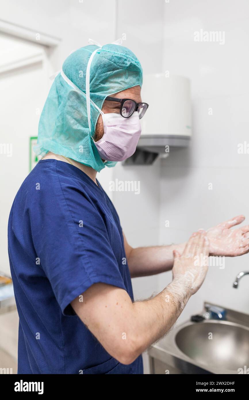 vétérinaire homme chirurgien dans les vêtements épi se préparant à opérer le lavage des mains dans l'évier de la clinique Banque D'Images
