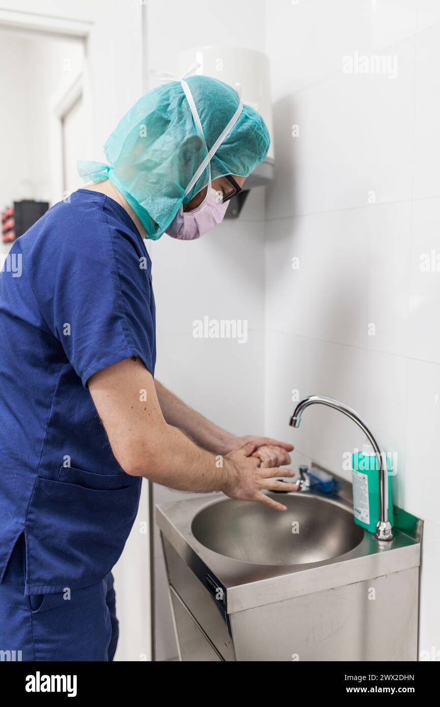 vétérinaire homme chirurgien dans les vêtements épi se préparant à opérer le lavage des mains dans l'évier de la clinique Banque D'Images