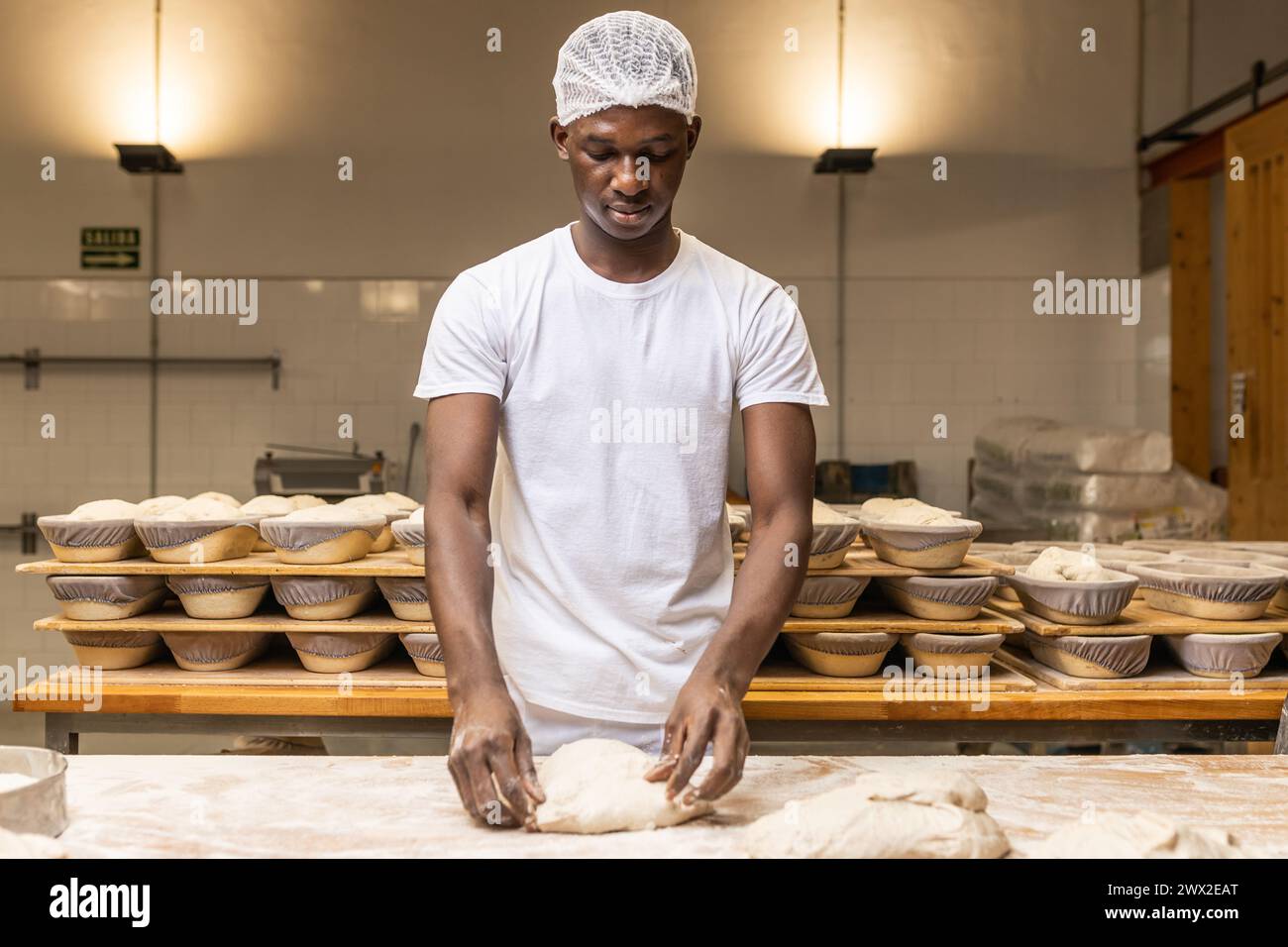 jeune homme noir travaillant dans une fabrique de pain, apprenant le métier. Banque D'Images