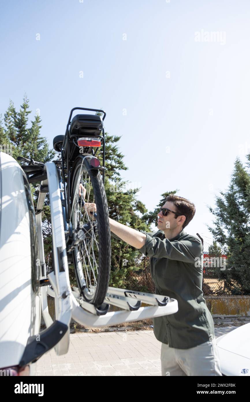 jeune homme d'affaires monte e-bike, chargeant le vélo sur le porte-vélos de son véhicule Banque D'Images