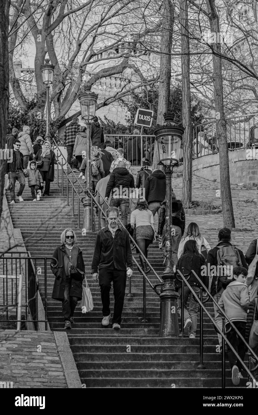 Paris, France - 17 février 2024 : vue des touristes qui montent et descendent les escaliers pittoresques avec les lanternes dans le quartier de Montmartre à Paris Banque D'Images