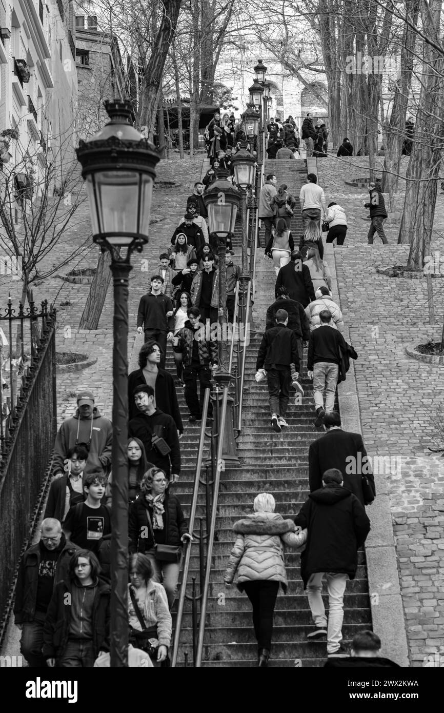 Paris, France - 17 février 2024 : vue des touristes qui montent et descendent les escaliers pittoresques avec les lanternes dans le quartier de Montmartre à Paris Banque D'Images