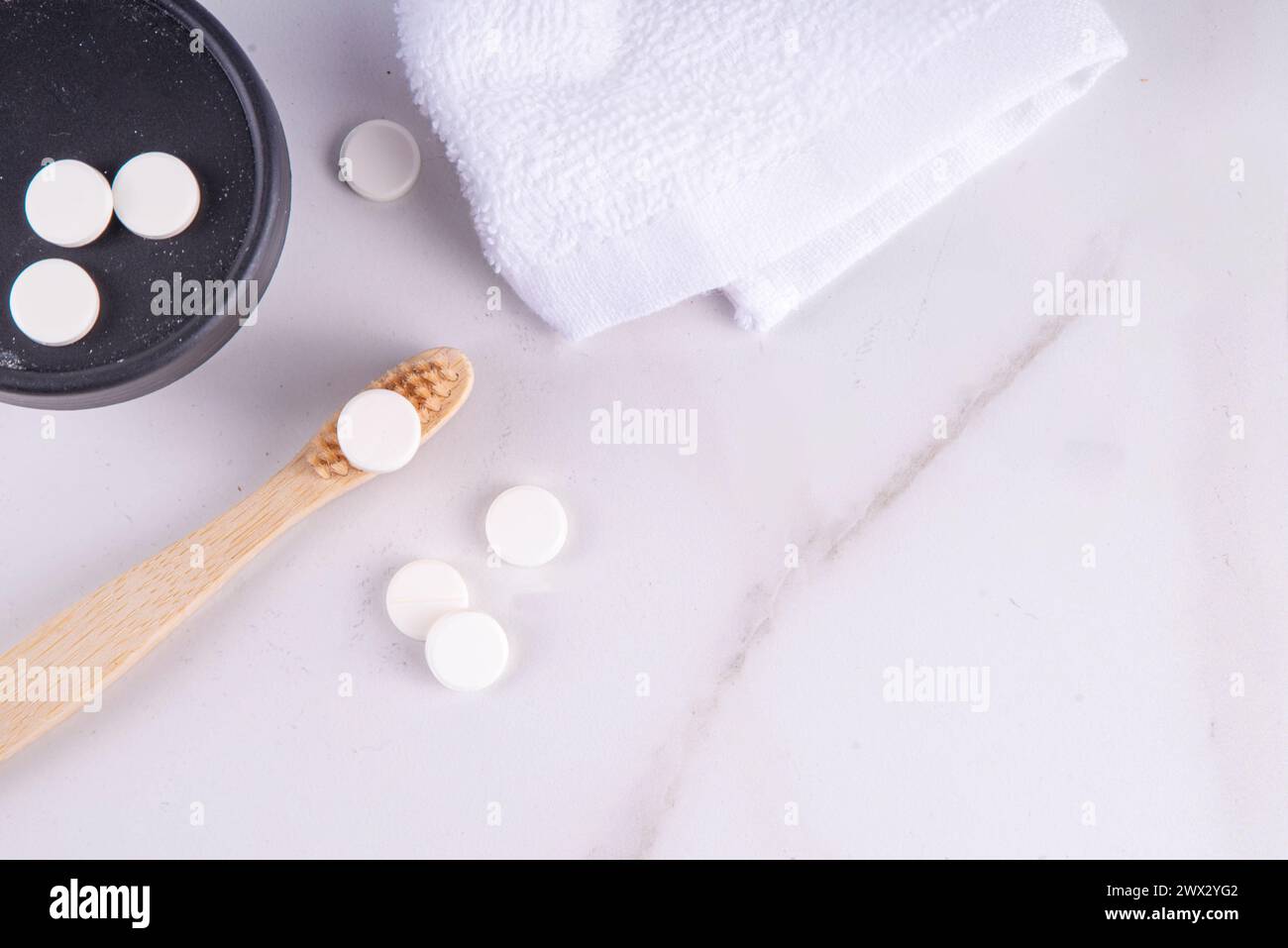 Comprimés de pilules de dentifrice sur brosse à dents, comprimé de dentifrice solide blanc avec brosse à dents en bambou sur fond de salle de bain blanc moderne Banque D'Images