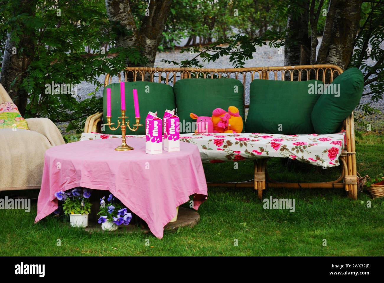 Canapé en osier dans le jardin avec table décorée de façon festive Banque D'Images