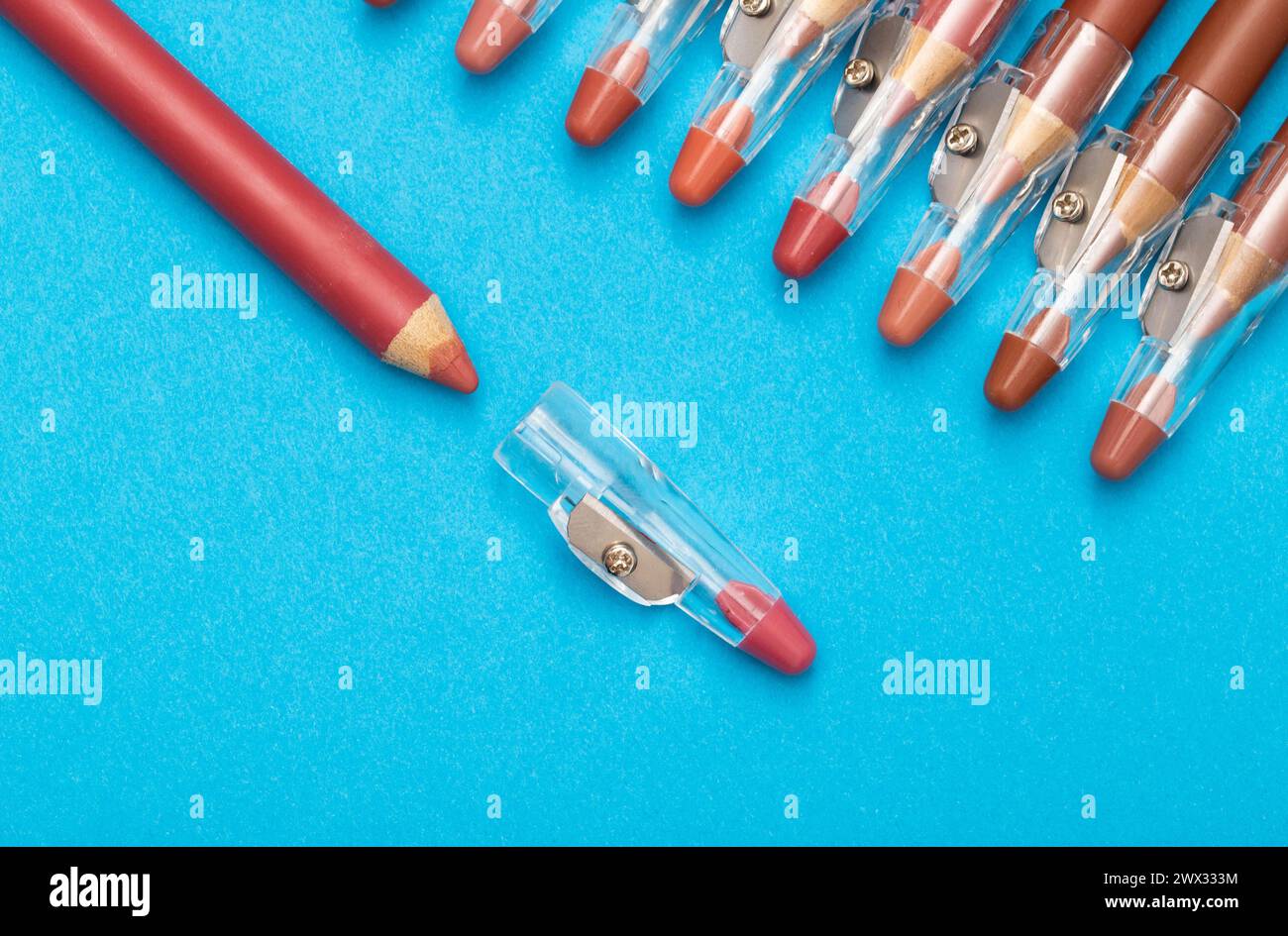 Crayons avec différentes nuances pour la peau des lèvres et le contour sur un fond bleu. Cosmétiques de maquillage de haute qualité. Banque D'Images