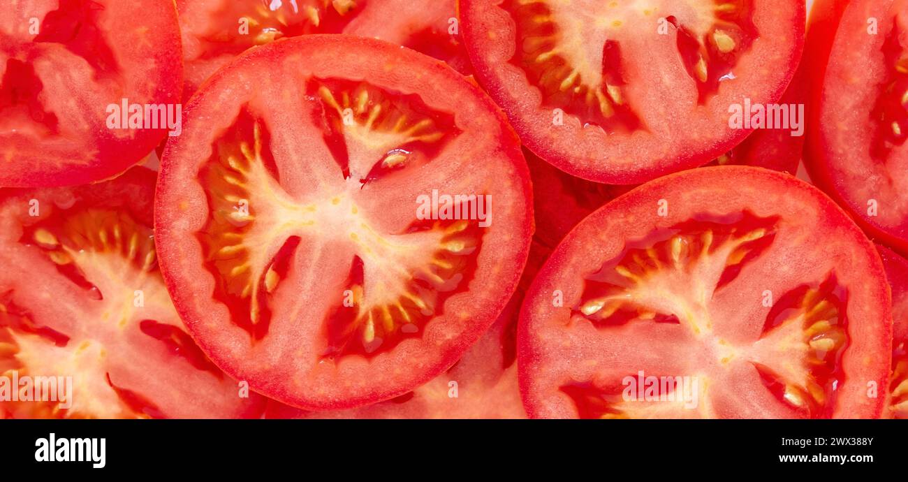 Couper les tomates biologiques rouges en gros plan. Fond alimentaire rouge juteux Banque D'Images