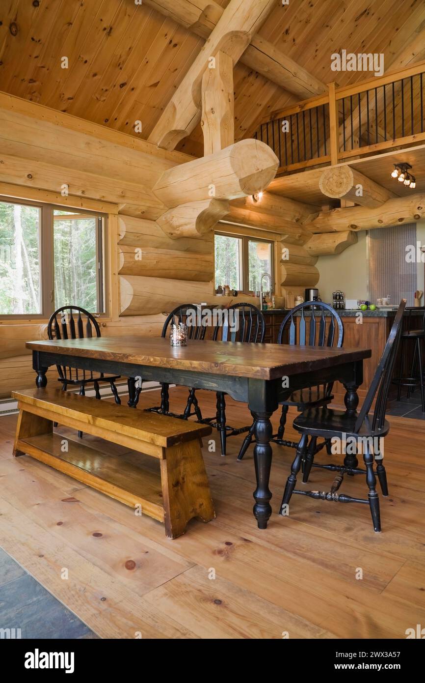 Table à manger en bois antique teinté noir avec chaises hautes arrondies et banc de repos en bois de pin dans la salle à manger à aire ouverte et la cuisine à l'intérieur Banque D'Images