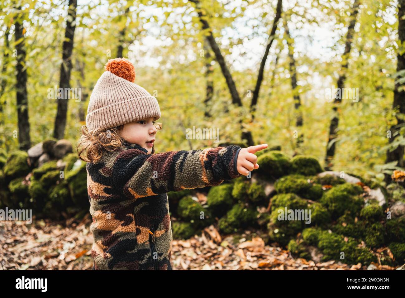 portrait de joli petit garçon à la mode avec chapeau dans une forêt pointant le doigt vers l'avant Banque D'Images