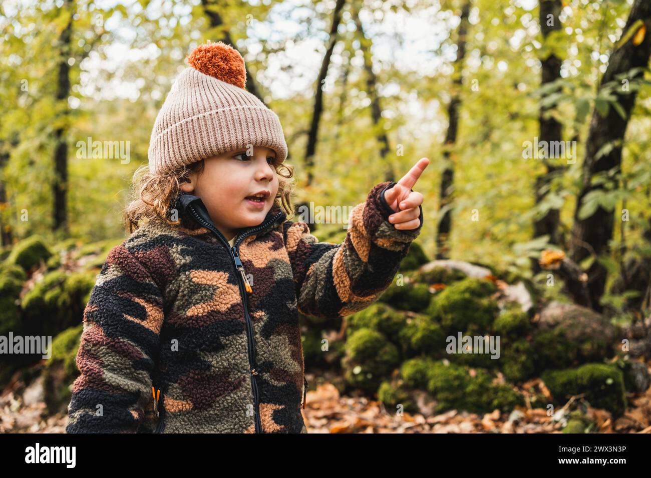 portrait de joli petit garçon à la mode avec chapeau dans une forêt pointant le doigt vers l'avant Banque D'Images