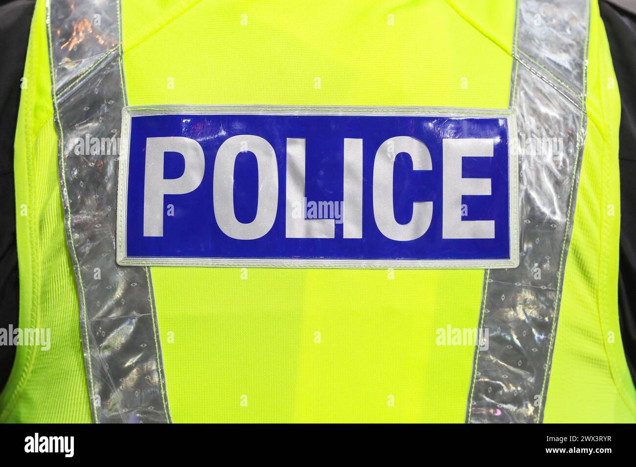 Signe de police à l'arrière d'une veste fluorescente émise par la police Banque D'Images