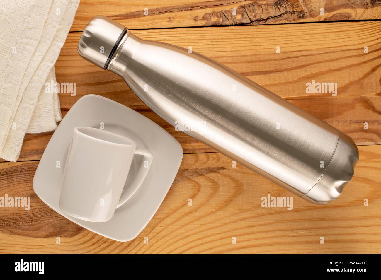 Une bouteille thermos en métal avec tasse en céramique blanche sur table en bois, macro, vue de dessus. Banque D'Images