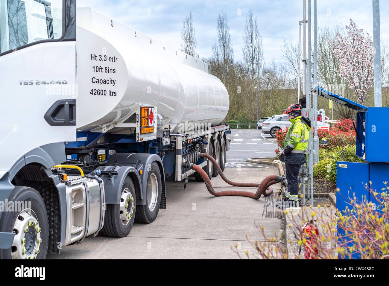 Camion-citerne remplissant les réservoirs de carburant sur la piste de la station-service du Royaume-Uni. Les tuyaux sont connectés, le carburant est pompé alors que le conducteur attend la fin de la livraison. Banque D'Images