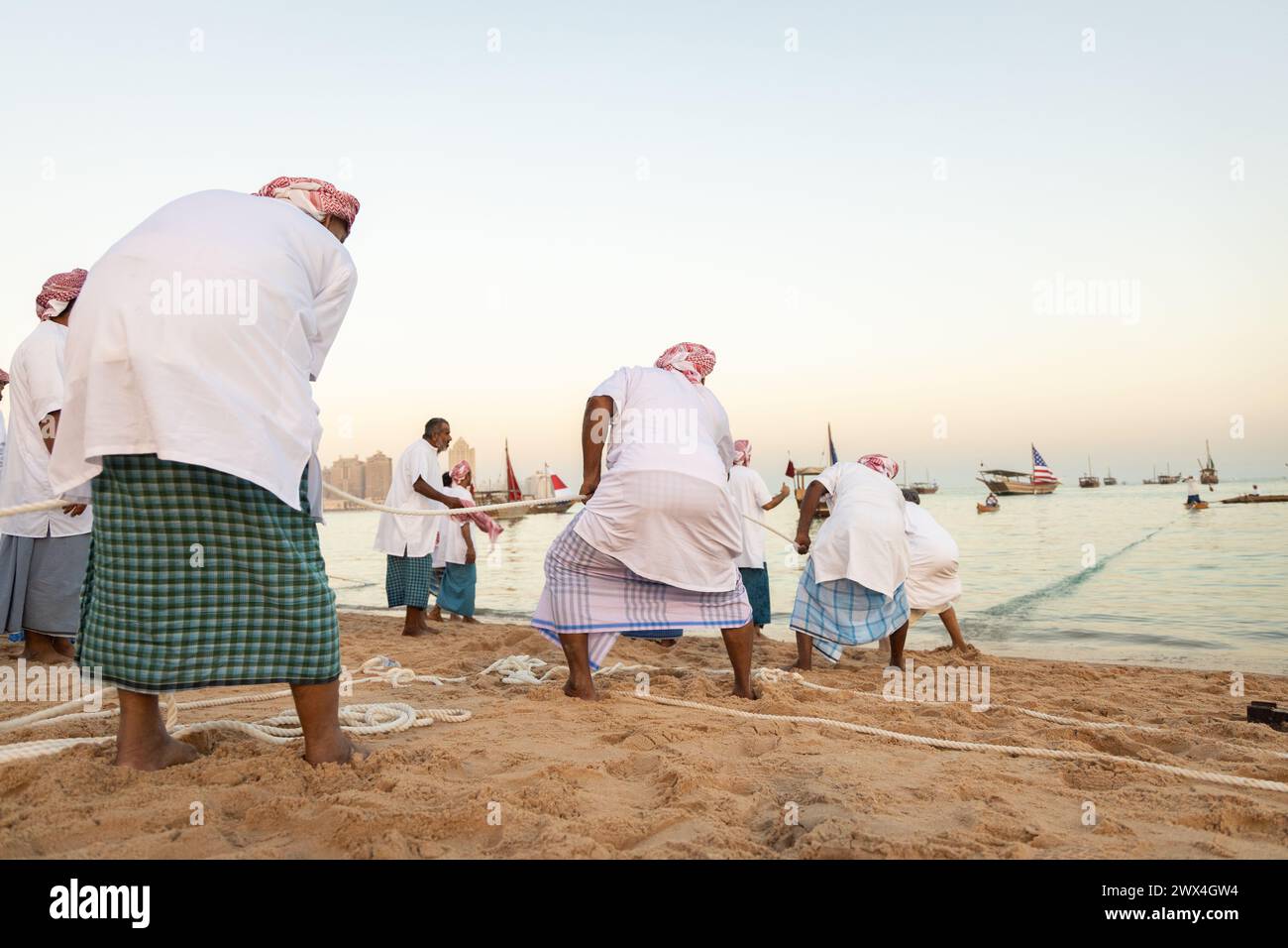 Des pêcheurs arabes non identifiés tirent leur senne hors de la mer sur la plage de Katara, Doha, Qatar. La pêche reste la principale source de revenus pour les habitants. Banque D'Images