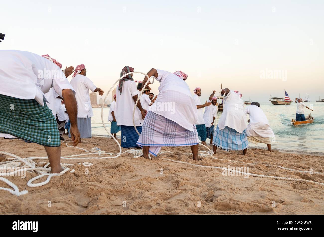 Des pêcheurs arabes non identifiés tirent leur senne hors de la mer sur la plage de Katara, Doha, Qatar. La pêche reste la principale source de revenus pour les habitants. Banque D'Images