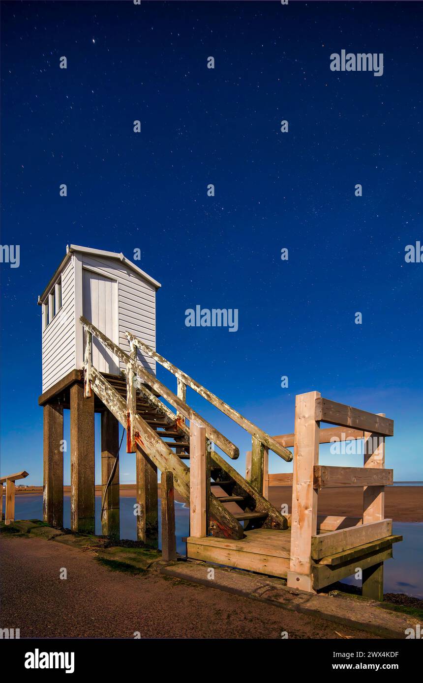 Une vue de nuit sous le clair de lune avec un ciel clair et les aurores boréales de la cabane du refuge sur la chaussée sur Lindisfarne dans le Northumberland Banque D'Images