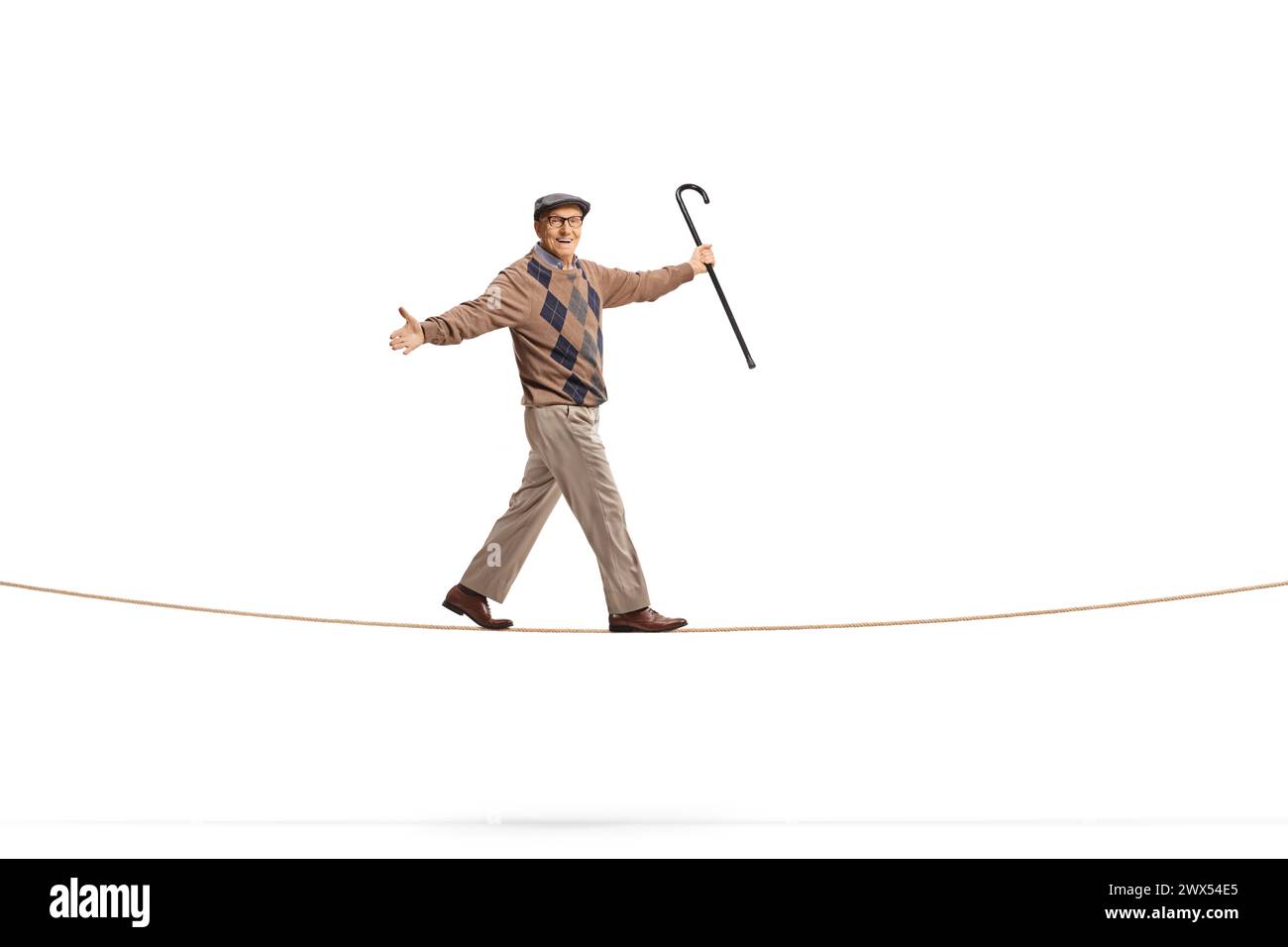 Plan complet d'un homme âgé tenant une canne et marchant sur une corde isolé sur fond blanc Banque D'Images