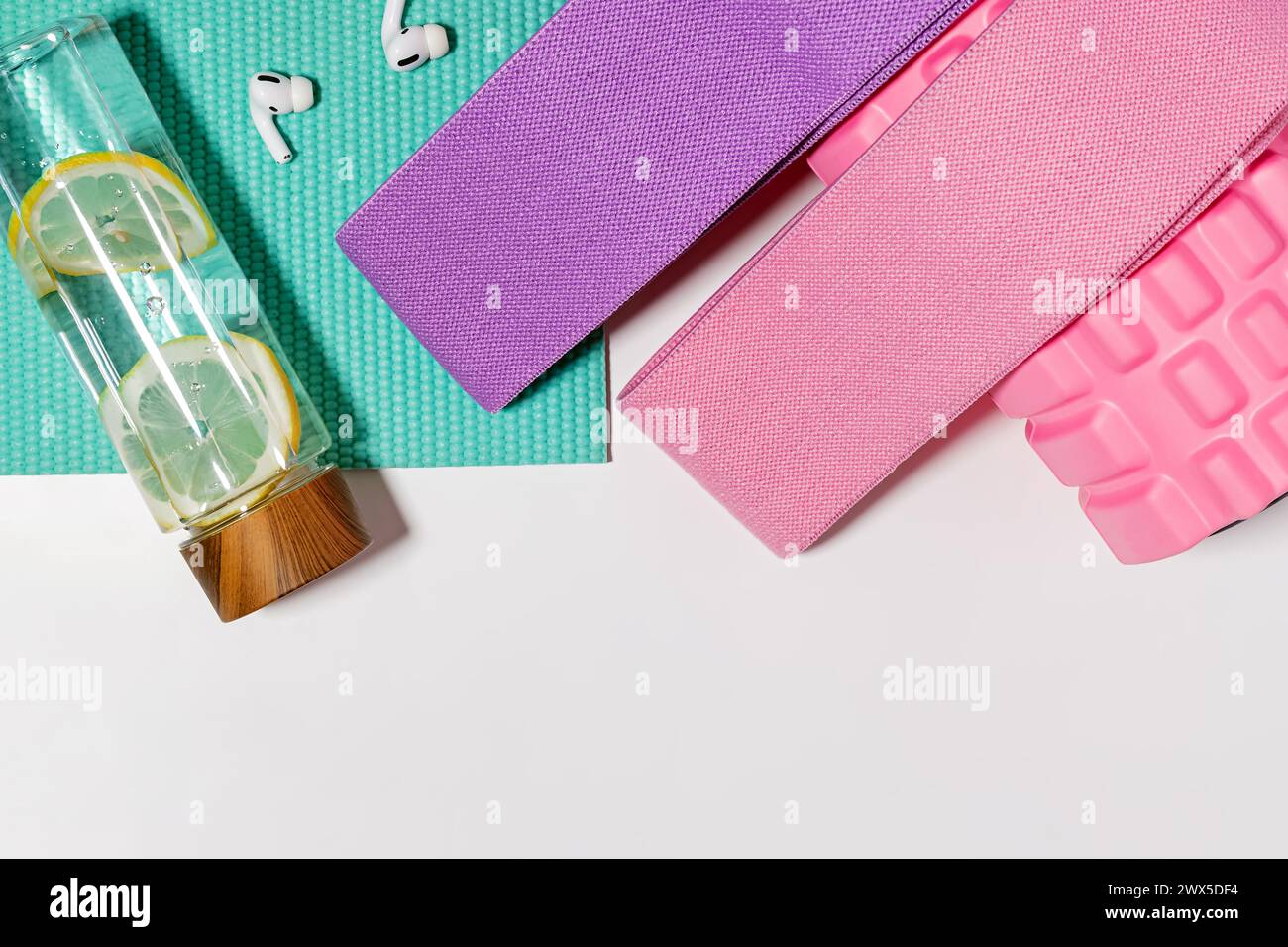 Accessoires d'entraînement et articles sur fond blanc, vue de dessus. Bouteille d'eau et bandes de résistance Banque D'Images