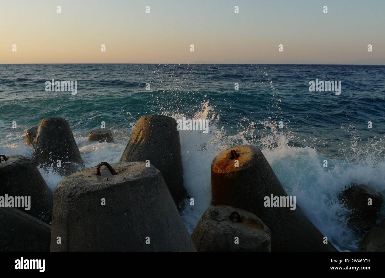 Les vagues de la mer s’écrasent contre un brise-lames composé de plusieurs modèles de quadrupèdes en béton qui fortifient un littoral Banque D'Images