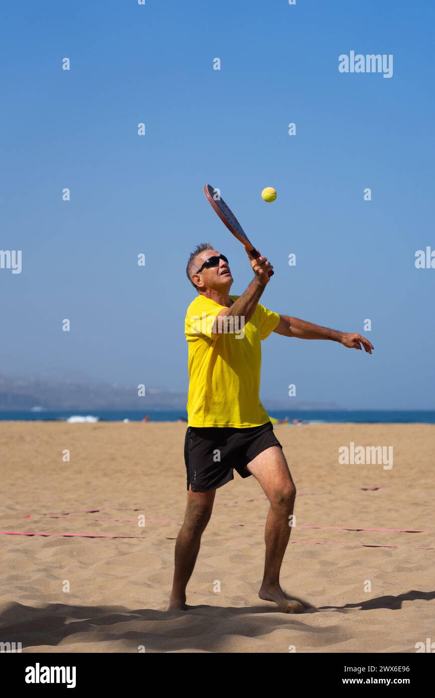 Homme de plus de 60 ans jouant au tennis de plage Banque D'Images