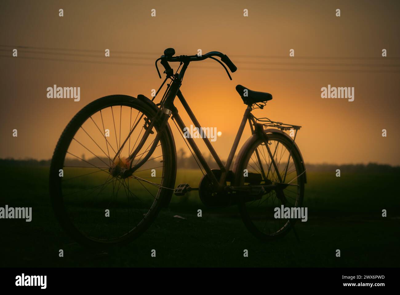 « Capturer l'essence du crépuscule : un vélo solitaire sur fond de coucher de soleil époustouflant, une scène intemporelle de sérénité et d'aventure. Banque D'Images