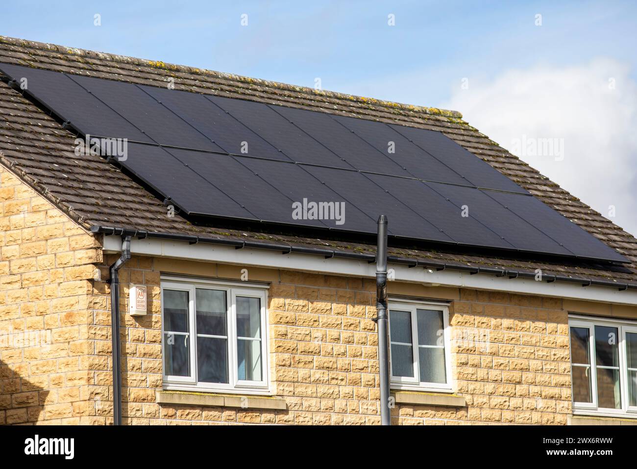 L'énergie solaire joue un rôle limité dans la production d'électricité au Royaume-Uni. Il y avait peu d'installations jusqu'en 2010, lorsque le gouvernement britannique a imposé des subventions sous la forme d'un tarif de rachat (FIT), payé par tous les consommateurs d'électricité. Au cours des années suivantes, le coût des panneaux photovoltaïques (PV) a baissé et les taux D'AJUSTEMENT pour les nouvelles installations ont été réduits progressivement jusqu'à ce que le régime ferme aux nouvelles applications en 2019. En 2023, plus de 14,4 gigawatts (GW) avaient été installés, dont un tiers solaire sur les toits. Maisons et maisons à Queensbury, West Yorkshire, Royaume-Uni avec des panneaux solaires par une journée ensoleillée. Banque D'Images