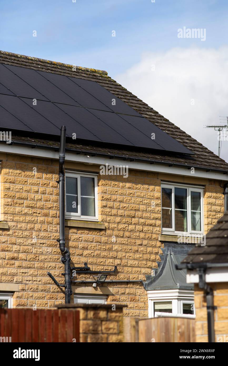 L'énergie solaire joue un rôle limité dans la production d'électricité au Royaume-Uni. Il y avait peu d'installations jusqu'en 2010, lorsque le gouvernement britannique a imposé des subventions sous la forme d'un tarif de rachat (FIT), payé par tous les consommateurs d'électricité. Au cours des années suivantes, le coût des panneaux photovoltaïques (PV) a baissé et les taux D'AJUSTEMENT pour les nouvelles installations ont été réduits progressivement jusqu'à ce que le régime ferme aux nouvelles applications en 2019. En 2023, plus de 14,4 gigawatts (GW) avaient été installés, dont un tiers solaire sur les toits. Maisons et maisons à Queensbury, West Yorkshire, Royaume-Uni avec des panneaux solaires par une journée ensoleillée. Banque D'Images