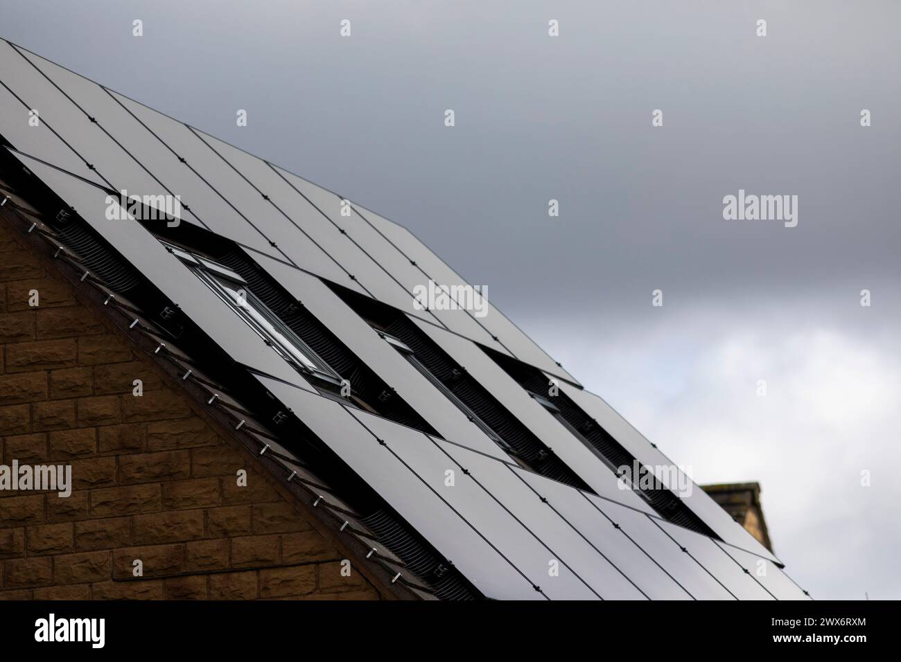 L'énergie solaire joue un rôle limité dans la production d'électricité au Royaume-Uni. Il y avait peu d'installations jusqu'en 2010, lorsque le gouvernement britannique a imposé des subventions sous la forme d'un tarif de rachat (FIT), payé par tous les consommateurs d'électricité. Au cours des années suivantes, le coût des panneaux photovoltaïques (PV) a baissé et les taux D'AJUSTEMENT pour les nouvelles installations ont été réduits progressivement jusqu'à ce que le régime ferme aux nouvelles applications en 2019. En 2023, plus de 14,4 gigawatts (GW) avaient été installés, dont un tiers solaire sur les toits. Maisons et maisons à Queensbury, West Yorkshire, Royaume-Uni avec des panneaux solaires par une journée ensoleillée. Banque D'Images