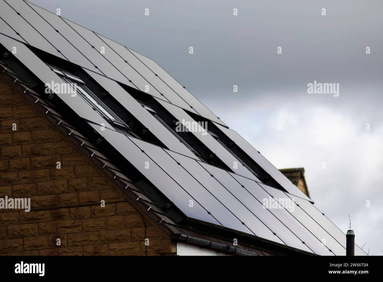 L'énergie solaire joue un rôle limité dans la production d'électricité au Royaume-Uni. Il y avait peu d'installations jusqu'en 2010, lorsque le gouvernement britannique a imposé des subventions sous la forme d'un tarif de rachat (FIT), payé par tous les consommateurs d'électricité. Au cours des années suivantes, le coût des panneaux photovoltaïques (PV) a baissé et les taux D'AJUSTEMENT pour les nouvelles installations ont été réduits progressivement jusqu'à ce que le régime ferme aux nouvelles applications en 2019. En 2023, plus de 14,4 gigawatts (GW) avaient été installés, dont un tiers solaire sur les toits. Maisons et maisons à Queensbury, West Yorkshire, Royaume-Uni avec des panneaux solaires par une journée ensoleillée. Banque D'Images