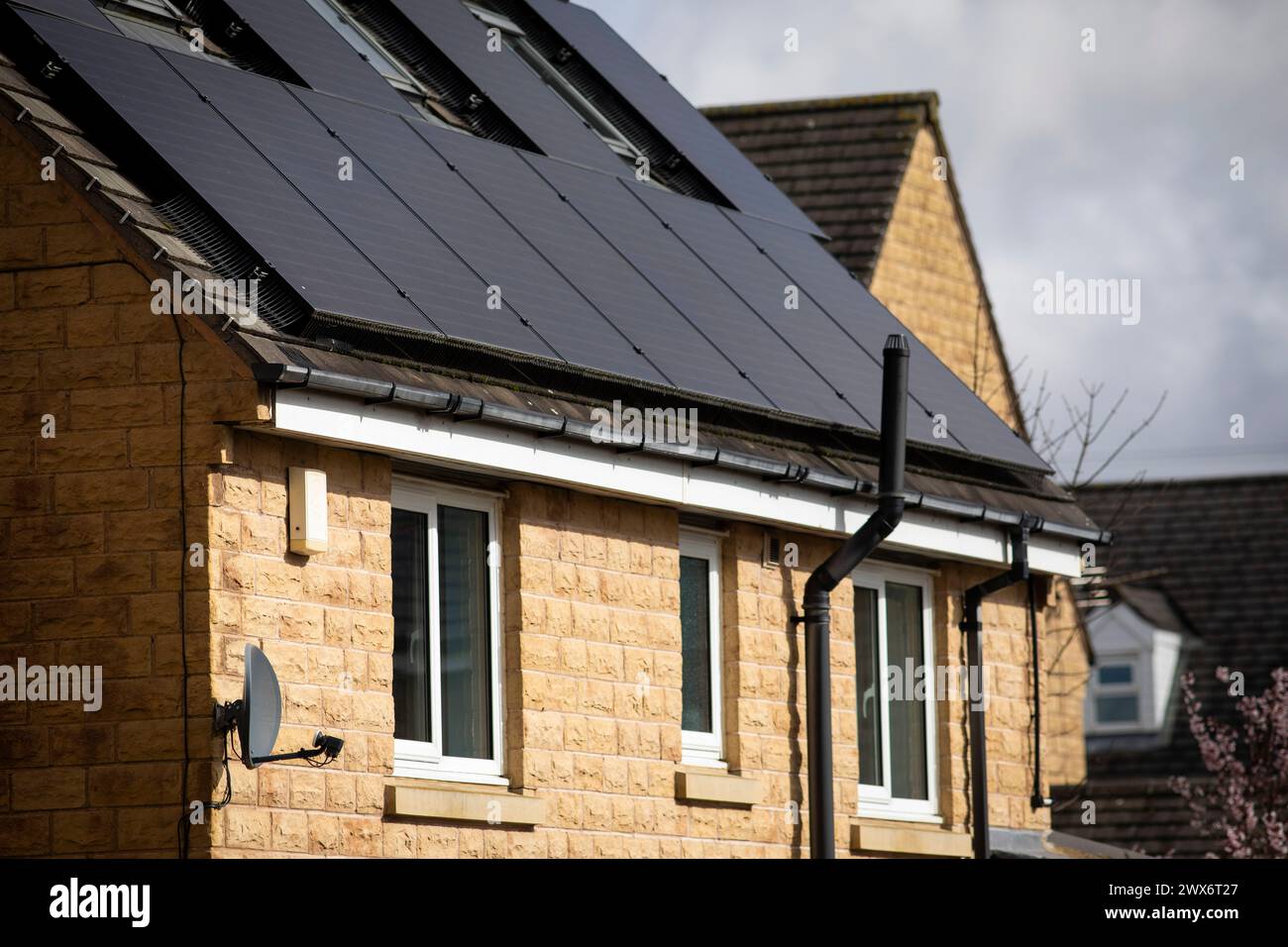 L'énergie solaire joue un rôle limité dans la production d'électricité au Royaume-Uni. Il y avait peu d'installations jusqu'en 2010, lorsque le gouvernement britannique a imposé des subventions sous la forme d'un tarif de rachat (FIT), payé par tous les consommateurs d'électricité. Au cours des années suivantes, le coût des panneaux photovoltaïques (PV) a baissé et les taux D'AJUSTEMENT pour les nouvelles installations ont été réduits progressivement jusqu'à ce que le régime ferme aux nouvelles applications en 2019. En 2023, plus de 14,4 gigawatts (GW) avaient été installés, dont un tiers solaire sur les toits. Maisons et maisons à Queensbury, West Yorkshire, Royaume-Uni avec des panneaux solaires par une journée ensoleillée. Banque D'Images
