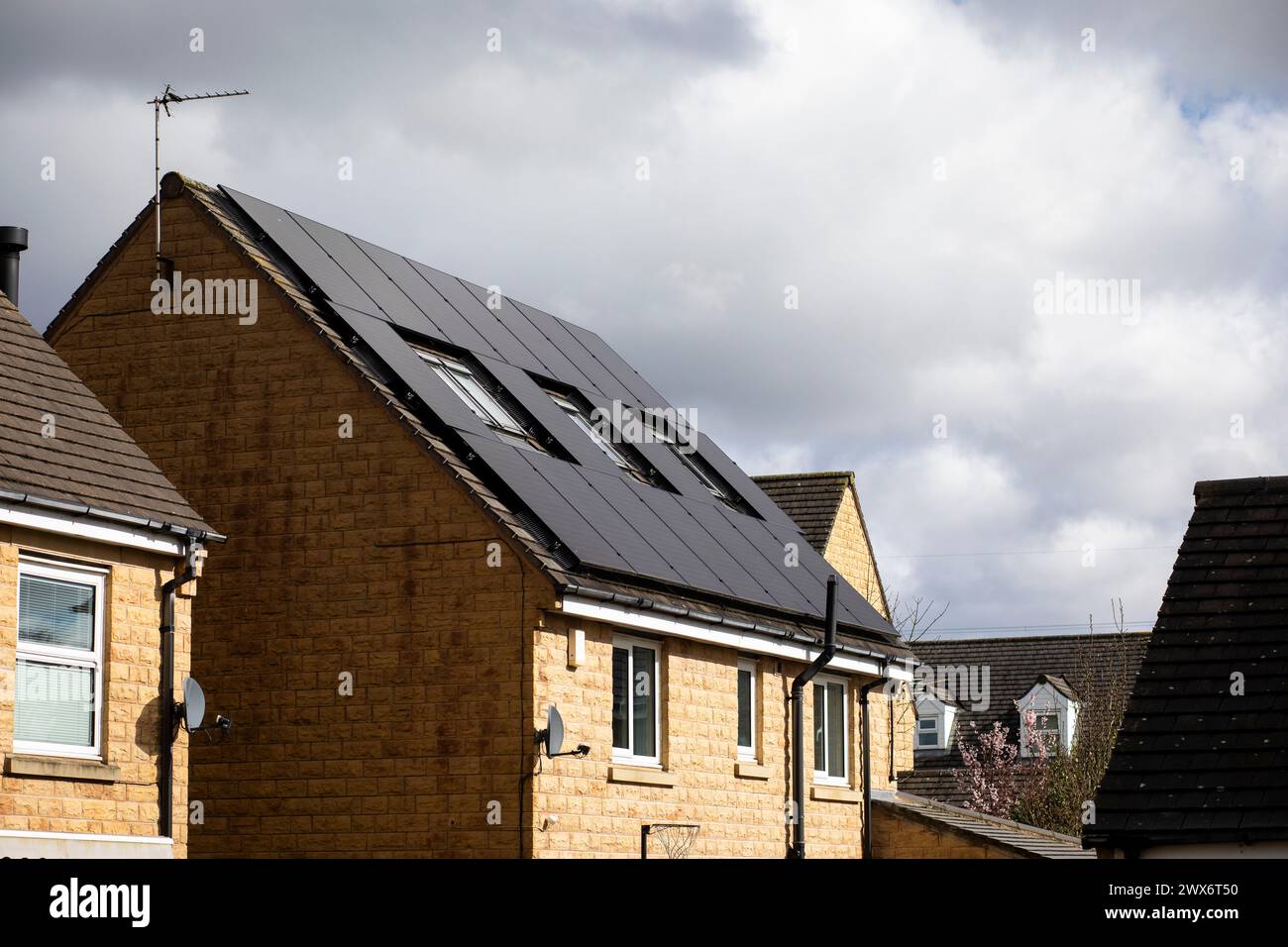 L'énergie solaire joue un rôle limité dans la production d'électricité au Royaume-Uni. Il y avait peu d'installations jusqu'en 2010, lorsque le gouvernement britannique a imposé des subventions sous la forme d'un tarif de rachat (FIT), payé par tous les consommateurs d'électricité. Au cours des années suivantes, le coût des panneaux photovoltaïques (PV) a baissé et les taux D'AJUSTEMENT pour les nouvelles installations ont été réduits progressivement jusqu'à ce que le régime ferme aux nouvelles applications en 2019. En 2023, plus de 14,4 gigawatts (GW) avaient été installés, dont un tiers solaire sur les toits. Maisons et maisons à Queensbury, West Yorkshire, Royaume-Uni avec des panneaux solaires par une journée ensoleillée. Banque D'Images