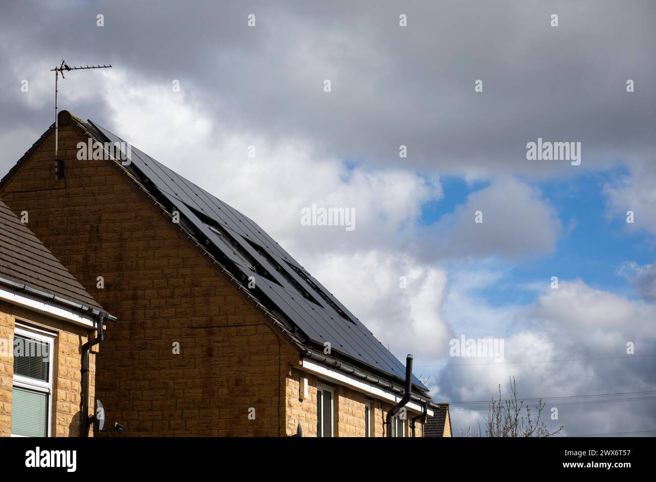 L'énergie solaire joue un rôle limité dans la production d'électricité au Royaume-Uni. Il y avait peu d'installations jusqu'en 2010, lorsque le gouvernement britannique a imposé des subventions sous la forme d'un tarif de rachat (FIT), payé par tous les consommateurs d'électricité. Au cours des années suivantes, le coût des panneaux photovoltaïques (PV) a baissé et les taux D'AJUSTEMENT pour les nouvelles installations ont été réduits progressivement jusqu'à ce que le régime ferme aux nouvelles applications en 2019. En 2023, plus de 14,4 gigawatts (GW) avaient été installés, dont un tiers solaire sur les toits. Maisons et maisons à Queensbury, West Yorkshire, Royaume-Uni avec des panneaux solaires par une journée ensoleillée. Banque D'Images