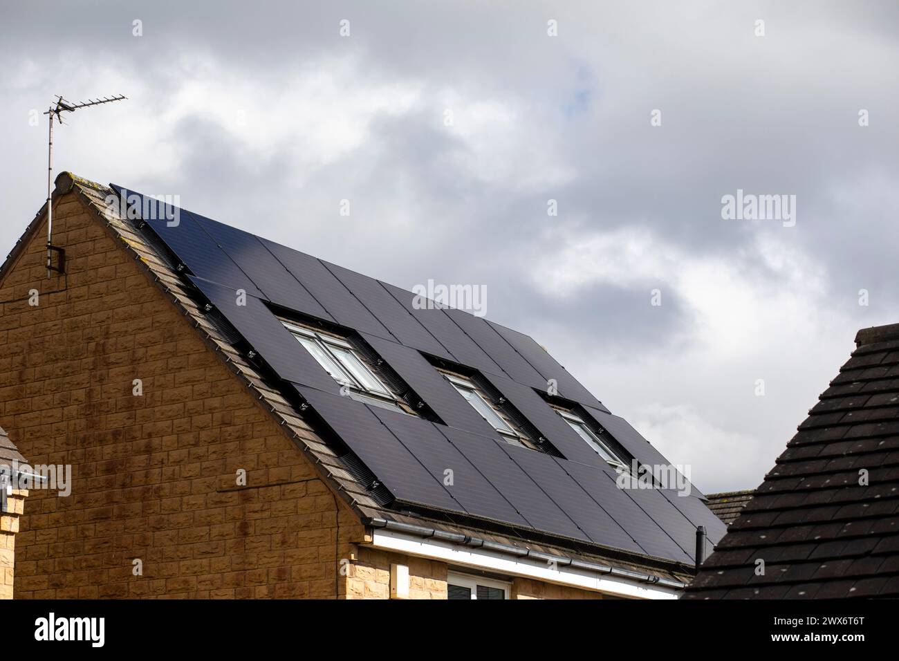 L'énergie solaire joue un rôle limité dans la production d'électricité au Royaume-Uni. Il y avait peu d'installations jusqu'en 2010, lorsque le gouvernement britannique a imposé des subventions sous la forme d'un tarif de rachat (FIT), payé par tous les consommateurs d'électricité. Au cours des années suivantes, le coût des panneaux photovoltaïques (PV) a baissé et les taux D'AJUSTEMENT pour les nouvelles installations ont été réduits progressivement jusqu'à ce que le régime ferme aux nouvelles applications en 2019. En 2023, plus de 14,4 gigawatts (GW) avaient été installés, dont un tiers solaire sur les toits. Maisons et maisons à Queensbury, West Yorkshire, Royaume-Uni avec des panneaux solaires par une journée ensoleillée. Banque D'Images