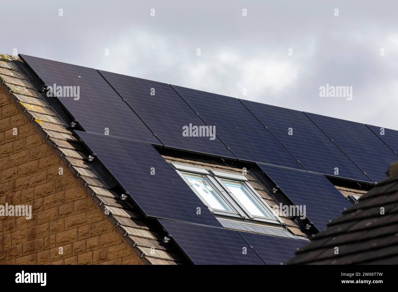 L'énergie solaire joue un rôle limité dans la production d'électricité au Royaume-Uni. Il y avait peu d'installations jusqu'en 2010, lorsque le gouvernement britannique a imposé des subventions sous la forme d'un tarif de rachat (FIT), payé par tous les consommateurs d'électricité. Au cours des années suivantes, le coût des panneaux photovoltaïques (PV) a baissé et les taux D'AJUSTEMENT pour les nouvelles installations ont été réduits progressivement jusqu'à ce que le régime ferme aux nouvelles applications en 2019. En 2023, plus de 14,4 gigawatts (GW) avaient été installés, dont un tiers solaire sur les toits. Maisons et maisons à Queensbury, West Yorkshire, Royaume-Uni avec des panneaux solaires par une journée ensoleillée. Banque D'Images