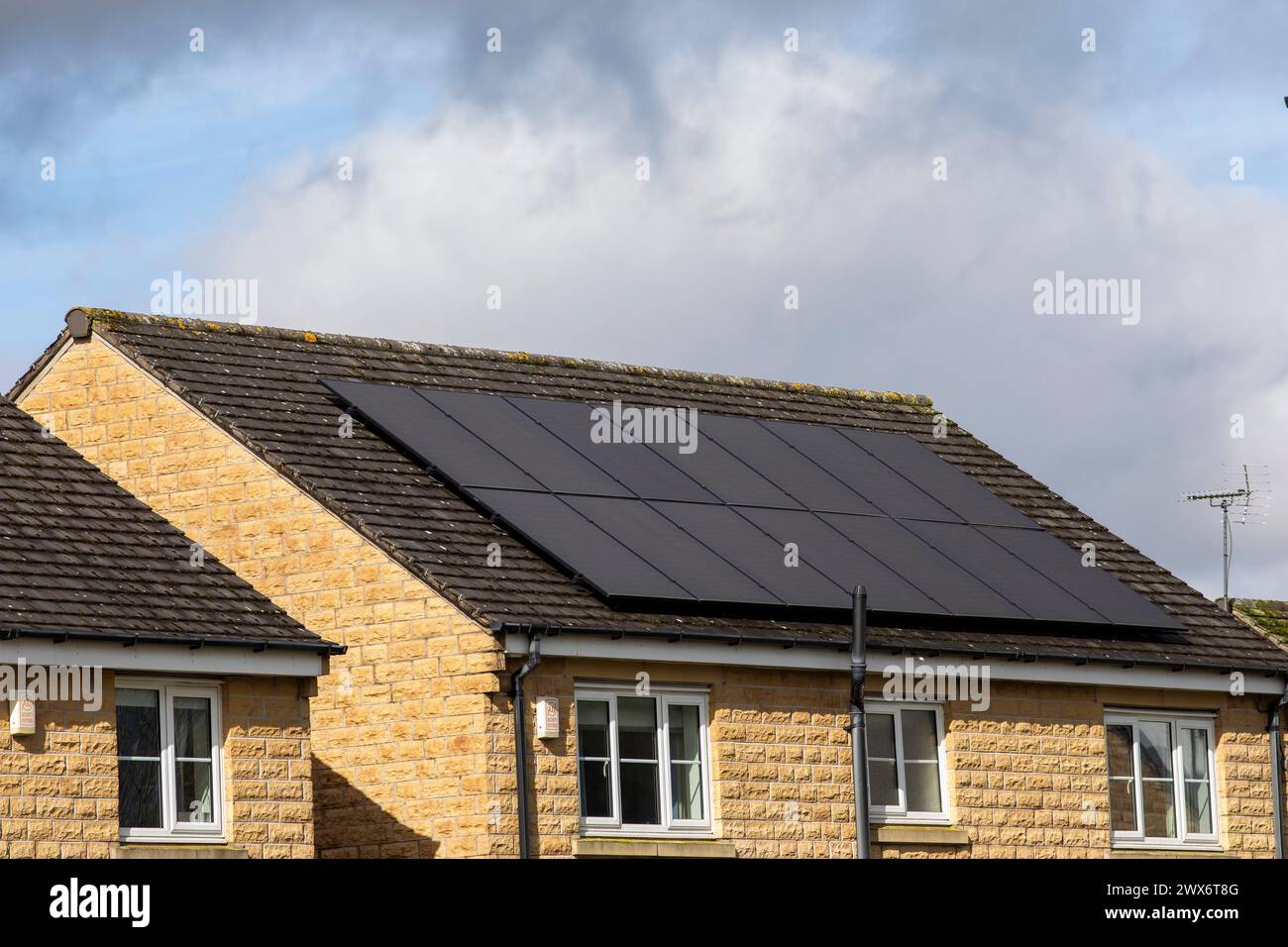 L'énergie solaire joue un rôle limité dans la production d'électricité au Royaume-Uni. Il y avait peu d'installations jusqu'en 2010, lorsque le gouvernement britannique a imposé des subventions sous la forme d'un tarif de rachat (FIT), payé par tous les consommateurs d'électricité. Au cours des années suivantes, le coût des panneaux photovoltaïques (PV) a baissé et les taux D'AJUSTEMENT pour les nouvelles installations ont été réduits progressivement jusqu'à ce que le régime ferme aux nouvelles applications en 2019. En 2023, plus de 14,4 gigawatts (GW) avaient été installés, dont un tiers solaire sur les toits. Maisons et maisons à Queensbury, West Yorkshire, Royaume-Uni avec des panneaux solaires par une journée ensoleillée. Banque D'Images