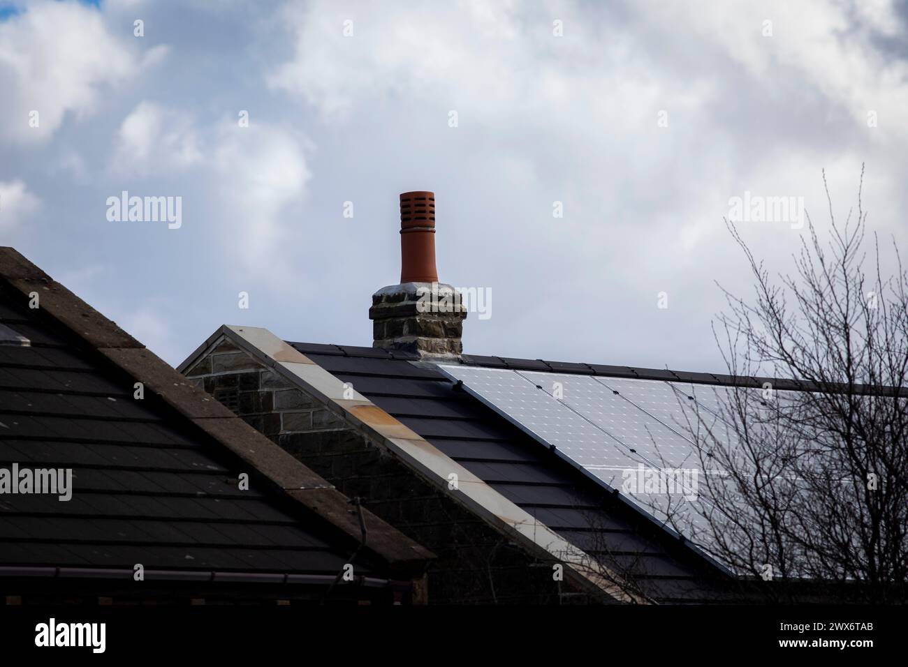 L'énergie solaire joue un rôle limité dans la production d'électricité au Royaume-Uni. Il y avait peu d'installations jusqu'en 2010, lorsque le gouvernement britannique a imposé des subventions sous la forme d'un tarif de rachat (FIT), payé par tous les consommateurs d'électricité. Au cours des années suivantes, le coût des panneaux photovoltaïques (PV) a baissé et les taux D'AJUSTEMENT pour les nouvelles installations ont été réduits progressivement jusqu'à ce que le régime ferme aux nouvelles applications en 2019. En 2023, plus de 14,4 gigawatts (GW) avaient été installés, dont un tiers solaire sur les toits. Maisons et maisons à Queensbury, West Yorkshire, Royaume-Uni avec des panneaux solaires par une journée ensoleillée. Banque D'Images