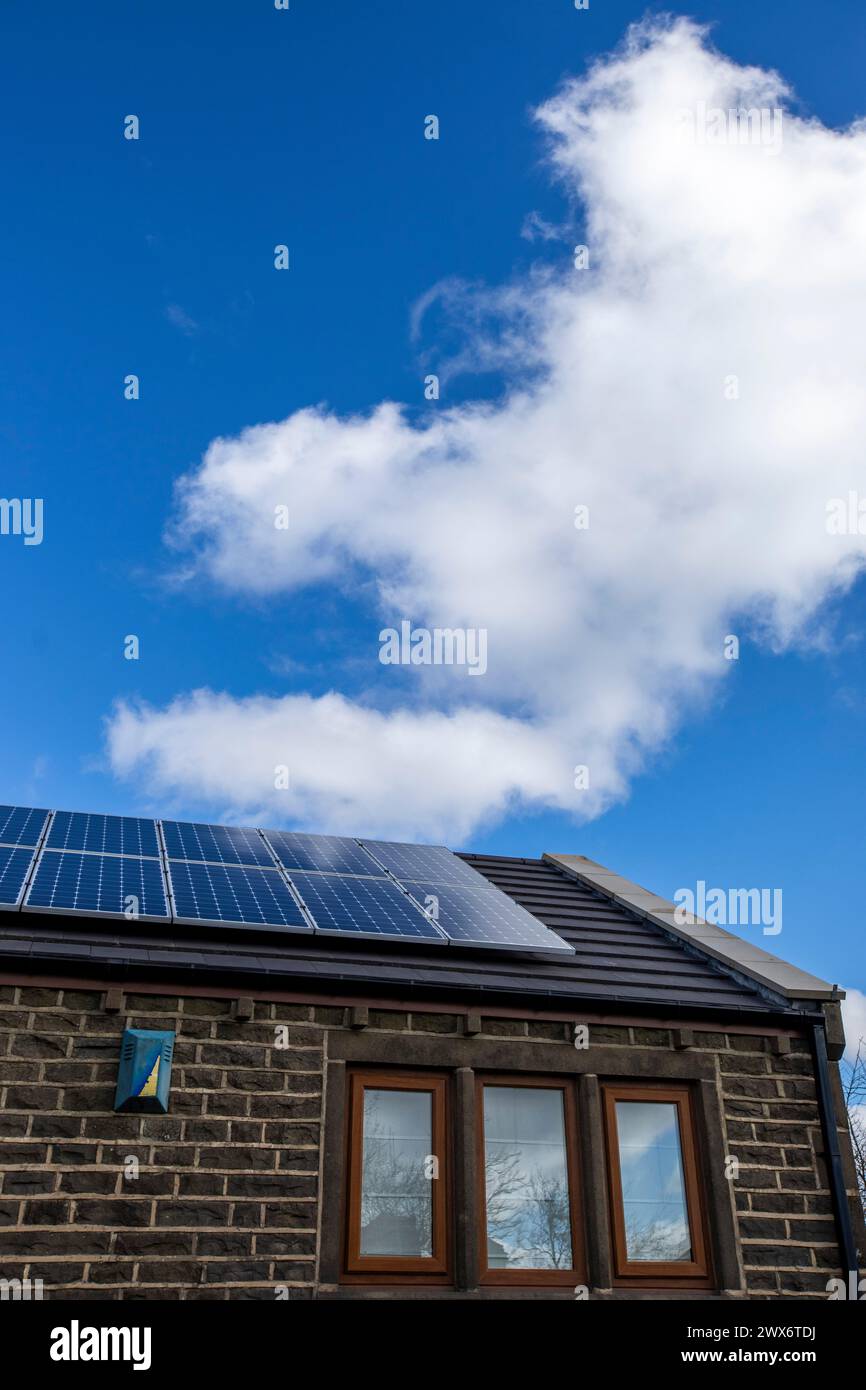 L'énergie solaire joue un rôle limité dans la production d'électricité au Royaume-Uni. Il y avait peu d'installations jusqu'en 2010, lorsque le gouvernement britannique a imposé des subventions sous la forme d'un tarif de rachat (FIT), payé par tous les consommateurs d'électricité. Au cours des années suivantes, le coût des panneaux photovoltaïques (PV) a baissé et les taux D'AJUSTEMENT pour les nouvelles installations ont été réduits progressivement jusqu'à ce que le régime ferme aux nouvelles applications en 2019. En 2023, plus de 14,4 gigawatts (GW) avaient été installés, dont un tiers solaire sur les toits. Maisons et maisons à Queensbury, West Yorkshire, Royaume-Uni avec des panneaux solaires par une journée ensoleillée. Banque D'Images