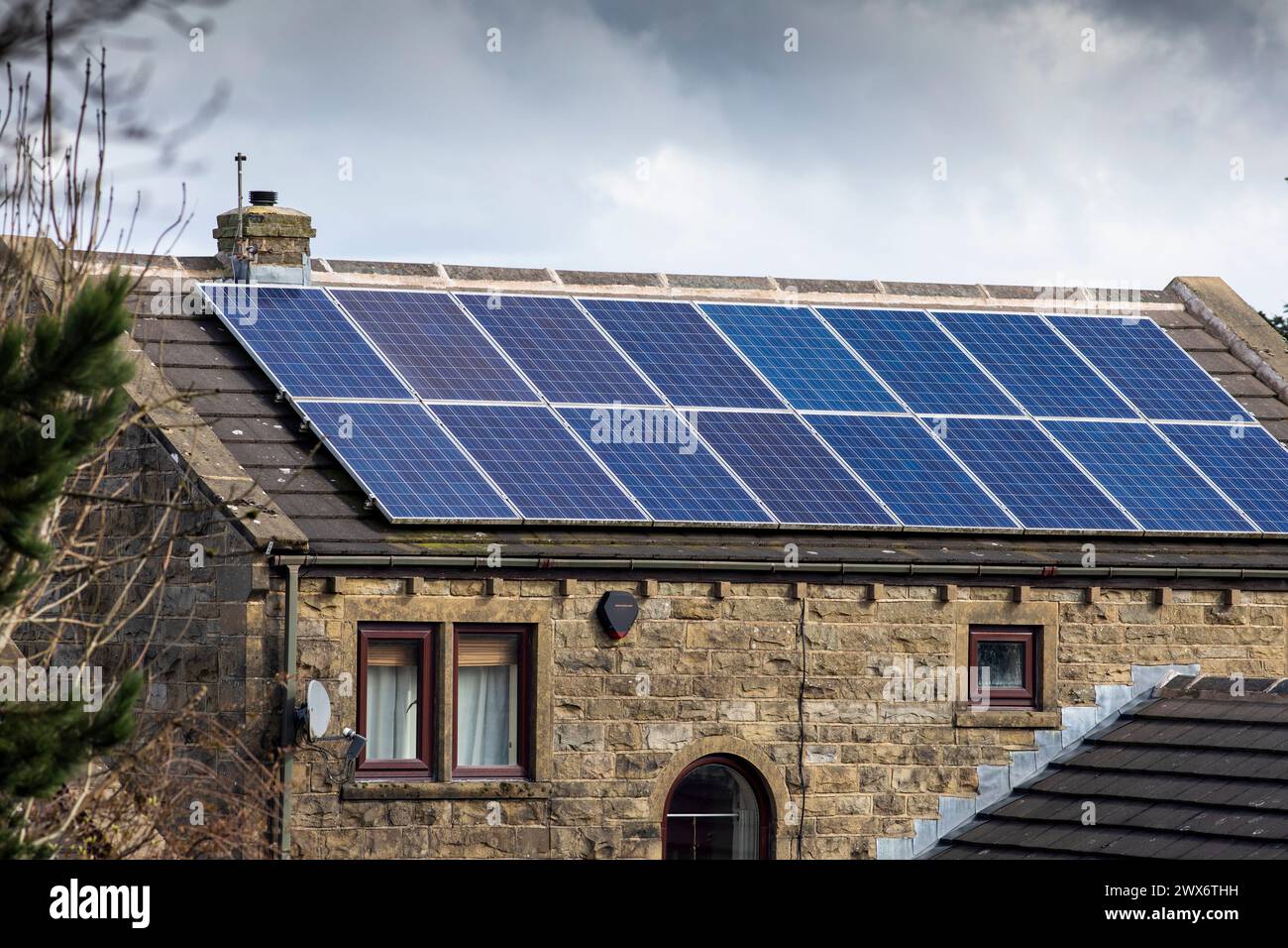 L'énergie solaire joue un rôle limité dans la production d'électricité au Royaume-Uni. Il y avait peu d'installations jusqu'en 2010, lorsque le gouvernement britannique a imposé des subventions sous la forme d'un tarif de rachat (FIT), payé par tous les consommateurs d'électricité. Au cours des années suivantes, le coût des panneaux photovoltaïques (PV) a baissé et les taux D'AJUSTEMENT pour les nouvelles installations ont été réduits progressivement jusqu'à ce que le régime ferme aux nouvelles applications en 2019. En 2023, plus de 14,4 gigawatts (GW) avaient été installés, dont un tiers solaire sur les toits. Maisons et maisons à Queensbury, West Yorkshire, Royaume-Uni avec des panneaux solaires par une journée ensoleillée. Banque D'Images