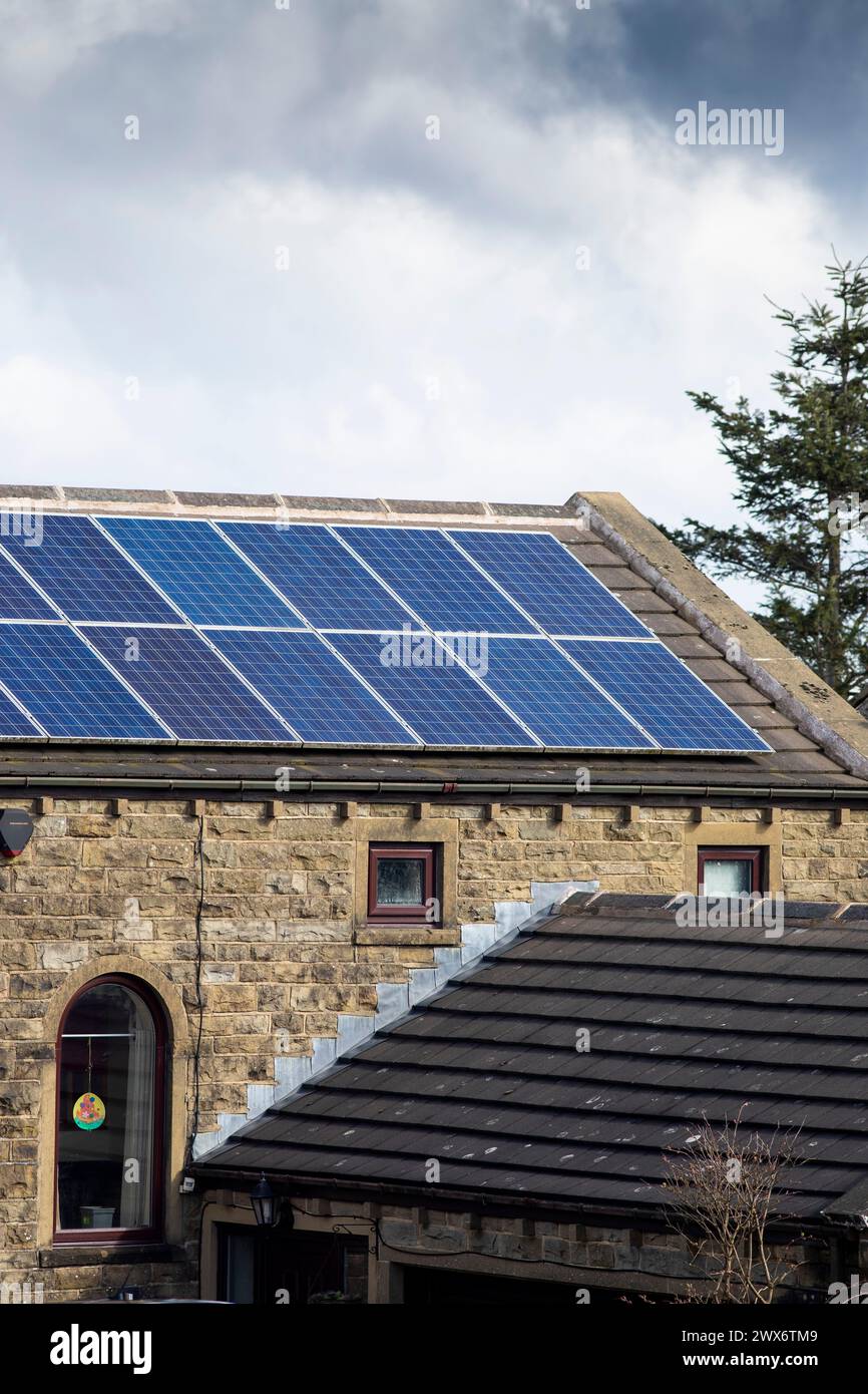 L'énergie solaire joue un rôle limité dans la production d'électricité au Royaume-Uni. Il y avait peu d'installations jusqu'en 2010, lorsque le gouvernement britannique a imposé des subventions sous la forme d'un tarif de rachat (FIT), payé par tous les consommateurs d'électricité. Au cours des années suivantes, le coût des panneaux photovoltaïques (PV) a baissé et les taux D'AJUSTEMENT pour les nouvelles installations ont été réduits progressivement jusqu'à ce que le régime ferme aux nouvelles applications en 2019. En 2023, plus de 14,4 gigawatts (GW) avaient été installés, dont un tiers solaire sur les toits. Maisons et maisons à Queensbury, West Yorkshire, Royaume-Uni avec des panneaux solaires par une journée ensoleillée. Banque D'Images